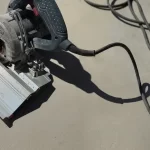 Suporte de Serra Mármore para corte em ângulo de 45 graus em uma superfície de concreto, com ferramenta elétrica instalada. Ideal para projetos de construção e obras de acabamento.